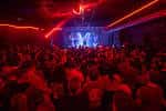 Interior del club durante un evento con iluminación roja y público