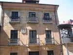 Vista frontal de la fachada principal de la Casa de Campomanes, destacando los balcones de hierro forjado