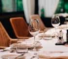 Detalle de una mesa puesta con copas de vino y sillas modernas en el interior del restaurante