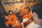 Interior de una celda de Alcotraz con clientes vestidos con monos naranjas disfrutando de la experiencia