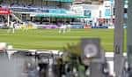 Detalle de un partido de cricket en el campo, con las tribunas al fondo