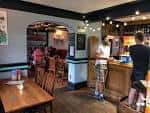 Interior del pub mostrando la barra y la zona de mesas de madera