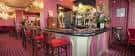 Detalle de la barra del bar con taburetes rojos y decoración interior