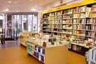 Interior de la librería con amplias estanterías de madera y mesas de exposición de libros