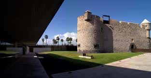Perspectiva desde la sombra de una estructura moderna hacia el castillo histórico
