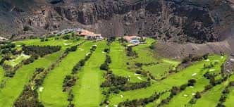 Vista aérea del campo de golf con edificios y terreno volcánico