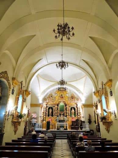 Interior de la iglesia con altar barroco y congregación sentada