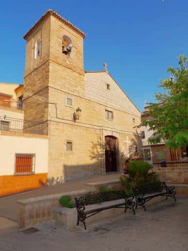 Vista lateral de la iglesia con campanario y plaza adoquinada