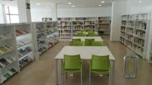 Sala de lectura principal con estanterías blancas y mesas para estudio