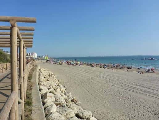 Vista panorámica de la playa con arena dorada y mar azul bajo un cielo despejado