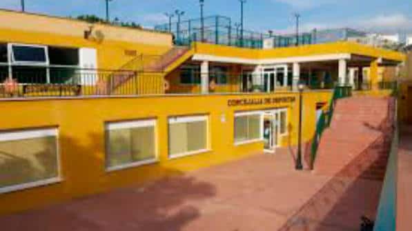 Fachada exterior amarilla del edificio principal con acceso a la concelleria de deportes