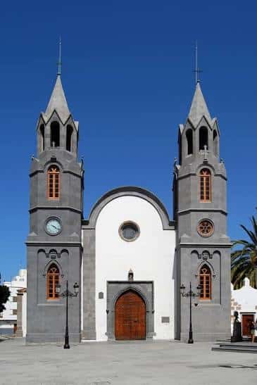 Fachada principal de la Basílica de San Juan Bautista con sus dos torres gemelas bajo un cielo azul despejado