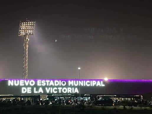 Fachada iluminada del estadio por la noche con letrero luminoso