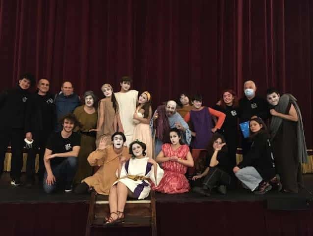 Grupo de actores y equipo en el escenario del Teatro Balbo con telón rojo al fondo