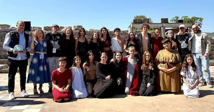 Cast y organizadores posando frente a ruinas antiguas durante evento cultural internacional
