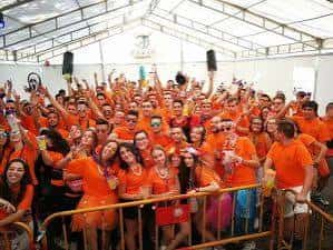 Grupo de asistentes vestidos de naranja celebrando en un evento al aire libre