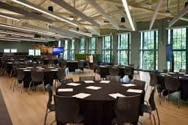 Sala de eventos con mesas redondas y sillas dispuestas para una cena o recepción