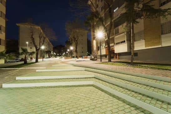 Vista nocturna del Paseo Virgen del Rocío con escalones de hormigón y pavimento de ladrillo