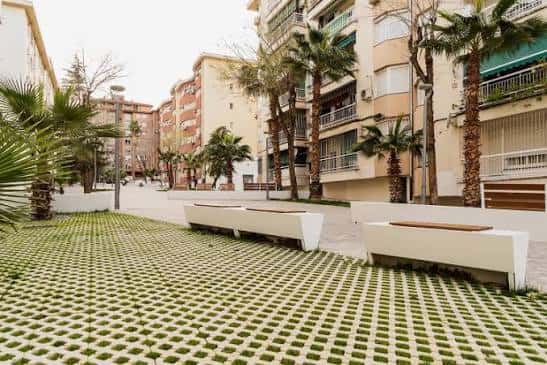 Área de descanso diurna con bancos modernos y césped en losas verdes