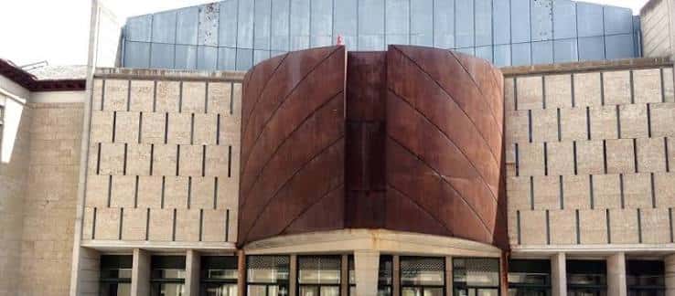 Vista exterior de la fachada moderna con detalles arquitectónicos en piedra y metal
