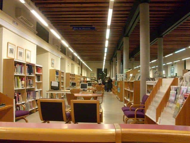 Interior de la biblioteca con estanterías llenas de libros y zonas de lectura