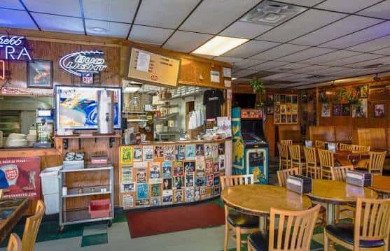 Interior del restaurante con mesas de madera, decoración retro y barra de servicio