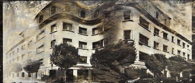 Fachada histórica del edificio con detalles arquitectónicos y árboles al frente