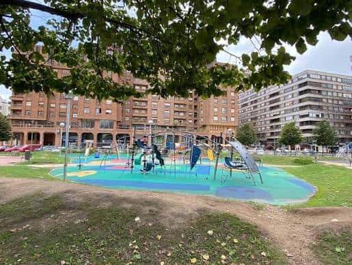 Vista general del parque infantil con equipamiento moderno y zonas de césped