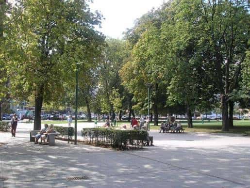 Paseo arbolado del parque con bancos y personas disfrutando del entorno