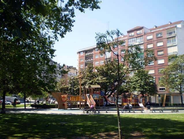 Área recreativa con juegos infantiles rodeada de árboles y edificios residenciales