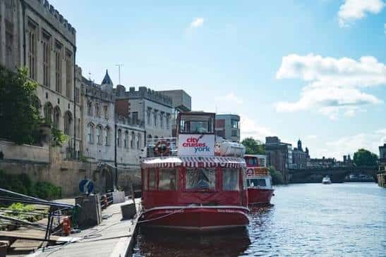 Embarcación roja de City Cruises amarrada en el muelle junto a edificios históricos de York