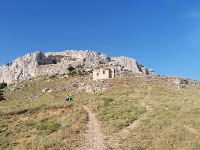 Vista panorámica del Refugio de la Mella en un día soleado con senderistas