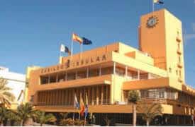 Vista exterior del Palacio del Cabildo Insular de Gran Canaria con fachada amarilla y banderas