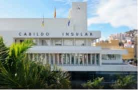 Fachada principal del edificio del Cabildo Insular en tonos blancos con vegetación tropical
