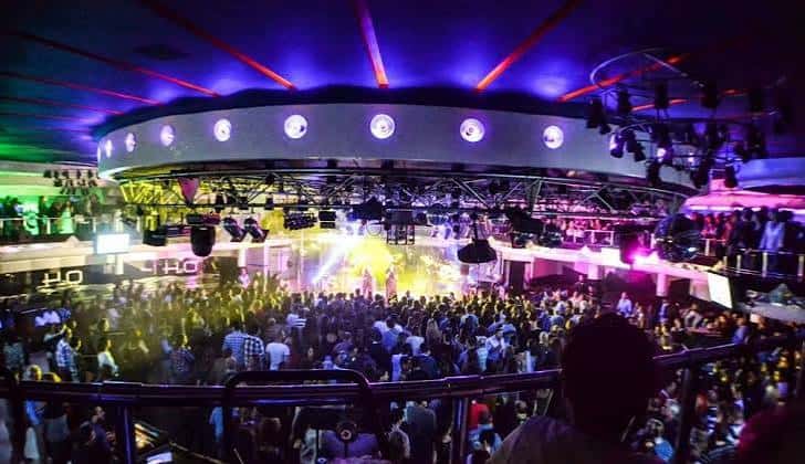 Interior de la discoteca Estilo con escenario iluminado, luces de neón y multitud bailando