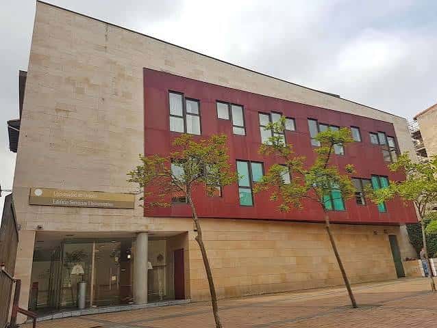 Vista exterior del Centro de Servicios Universitarios con fachada moderna y árboles jóvenes