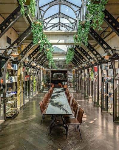 Gran sala de eventos con techo de cristal y decoración de plantas colgantes