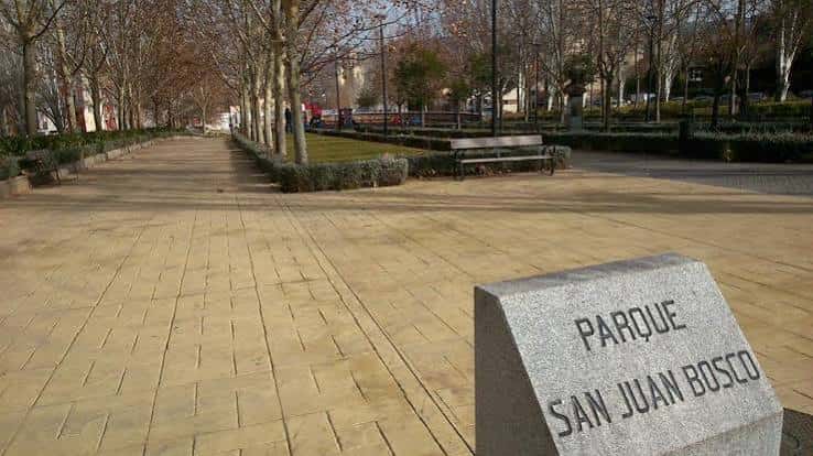 Señal de piedra con el nombre del parque y sendero pavimentado