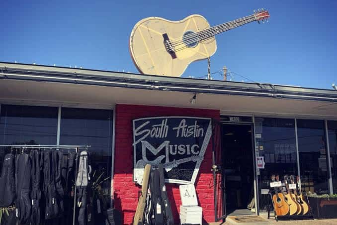 Entrada principal del local mostrando la señalización y guitarras expuestas