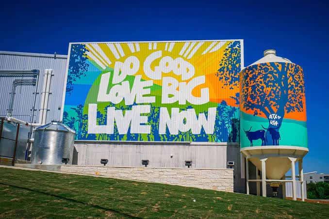 Fachada exterior de Fast Friends Beer Co con mural colorido y silos decorados