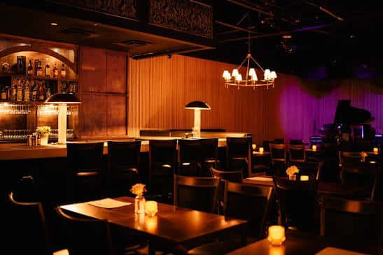Sala de eventos con mesas dispuestas para cena y piano en el fondo