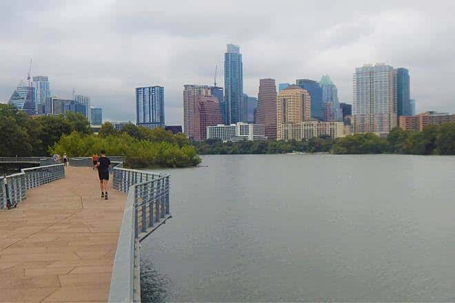Sendero bordeando el agua con el skyline de Austin al fondo