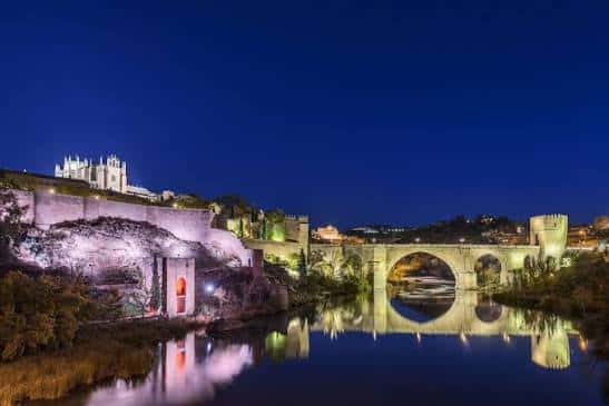 Iluminación nocturna del Puente de San Martín y la Alcazaba reflejadas en el agua