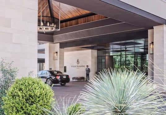 Entrada principal del hotel con portero y vehículo de bienvenida