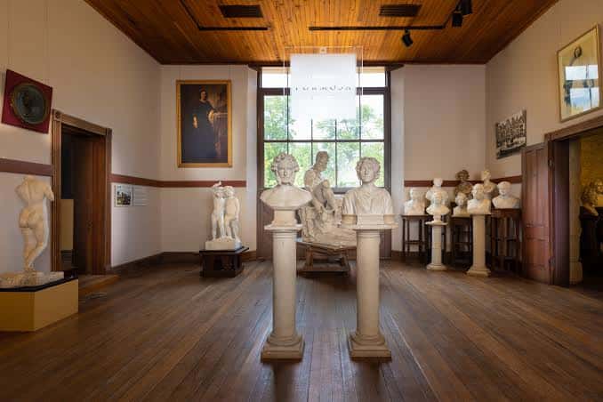 Interior del museo mostrando esculturas clásicas en un salón con suelo de madera