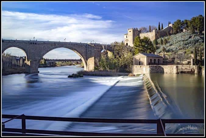 Panorámica diurna del molino con el Puente de Alcántara y la Alcazaba al fondo