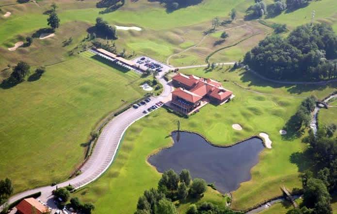 Vista aérea del club house principal con estacionamiento y lago adyacente