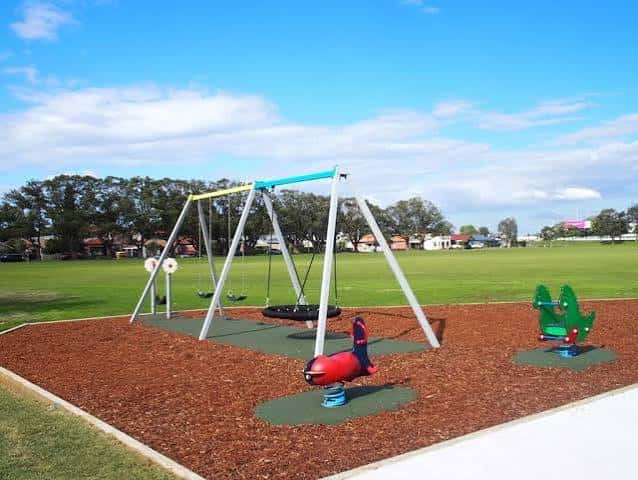 Juegos infantiles con columpios y balancines en un parque soleado