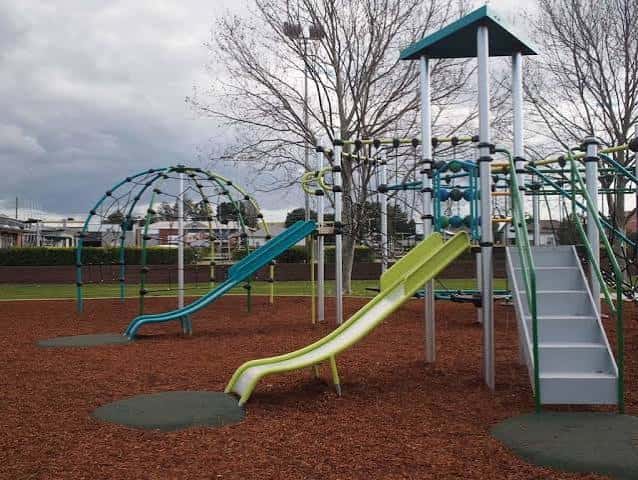 Área de juegos con toboganes curvos y estructuras de escalada bajo cielo nublado