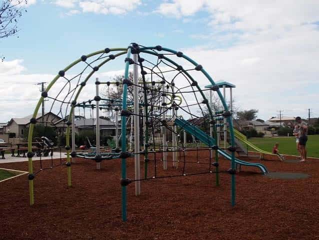 Gran estructura de red para trepar en el parque con niños jugando alrededor